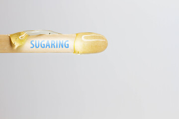 Sugaring inscription on a wooden spatula with hair removal wax.