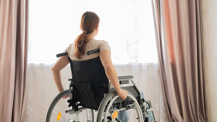 Caucasian woman in a wheelchair at the window. 