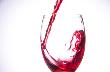 red wine pouring into glass isolated white background