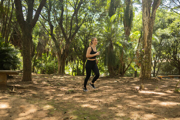 Fototapeta premium Young woman running and jogging at a park outdoors. Athlete female person during workout. High quality photo