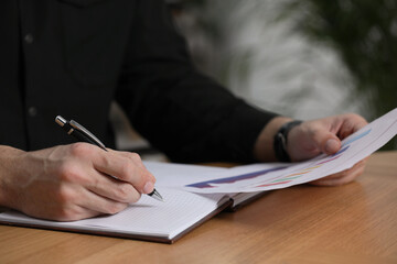 Man working with document at table in office, closeup