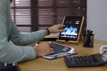 Fototapeta na wymiar Businessman working with tablet and chart in office, closeup. Forex trading