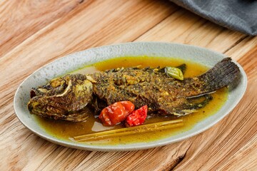 Tilapia Pesmol in a Oval Plate. Pesmol is a Sundanese Yellow Curry Spice Dish