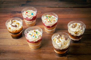 Six beautiful and delicious trifle cakes close-up on a rustic wooden background