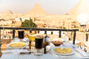 Traveler's breakfast. A table in an outdoor restaurant with a fantastically beautiful view of the great pyramids of Giza. Cairo. Egypt. Romantic dinner on roof with a beautiful view.