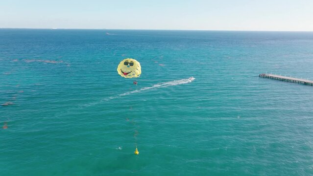 Tourists in parasail parachute dragged by boat in Caribbean ocean - aerial track
