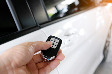 The man in the hand held the remote control of the car, he opened the remote control of the car door. To drive a car