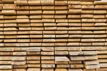 Stacked lumber filling background, wood texture. Stack of new wooden rods in the lumber warehouse.