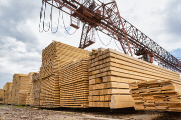Stacked lumber in the warehouse of the production site against the background of a cantilever...