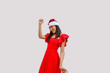 Young woman with red dress and Santa Claus hat dancing with a beautiful smile.