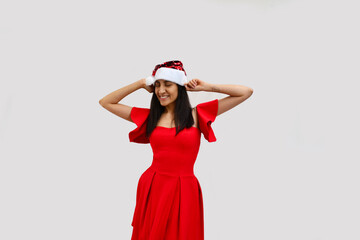 Young woman dancing with Santa Claus hat and red dress.