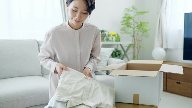 60p　ダンボールに衣服を入れるミドル女性