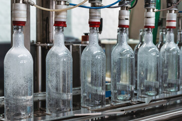 Equipment pours vodka into glass bottles on production line - obrazy, fototapety, plakaty
