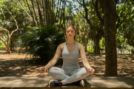 young woman meditating. practice of yoga and meditation on a sunny. day at a park. High quality photo.