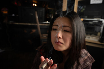 Asian girl smoking a weed joint getting high inhaling and exhaling  weed smoke  © contentzilla