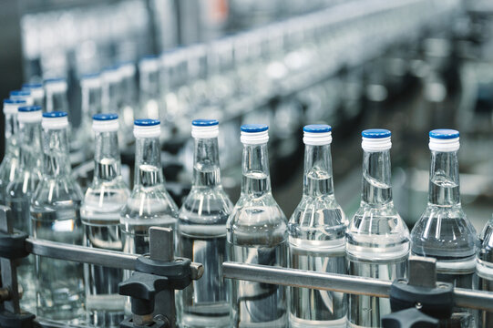 Closed glass bottles of upscale vodka transported by line