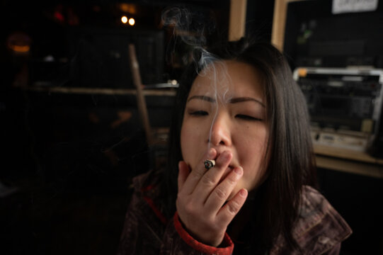 Asian Girl Smoking A Weed Joint Getting High Inhaling And Exhaling  Weed Smoke 