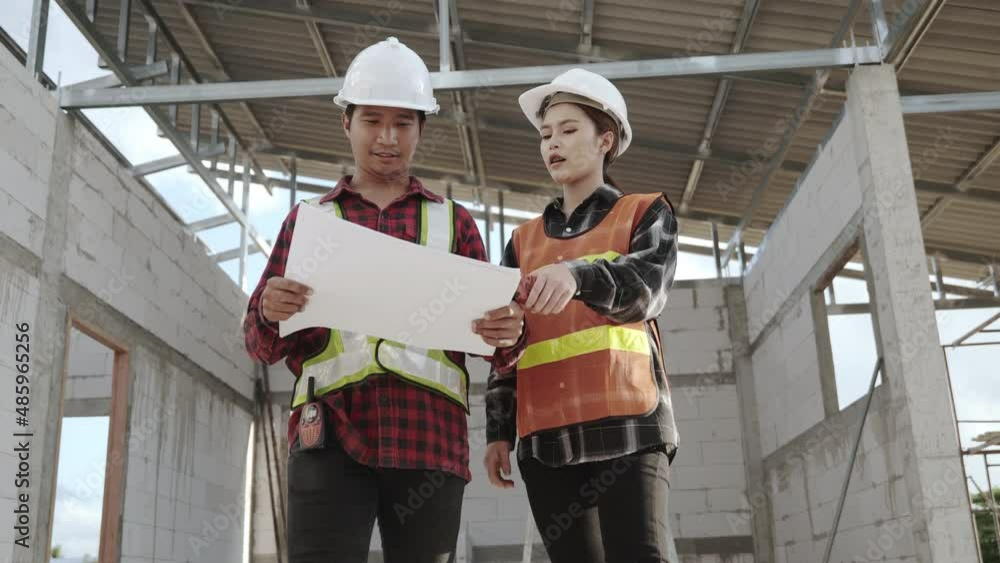 Poster architect and client discussing the plan with blueprint of the building at construction site