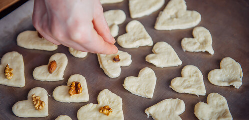 Raw homemade heart-shaped cookies on a baking sheet. Concept of fresh pastry, surprise for Valentine's day.