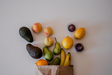 Different fruits in a crafted paper bag on the table. Healthy flat lay