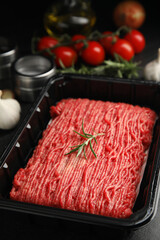 Plastic container with fresh minced meat on black table, closeup