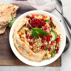 Bulgur and hummus salad on light background.