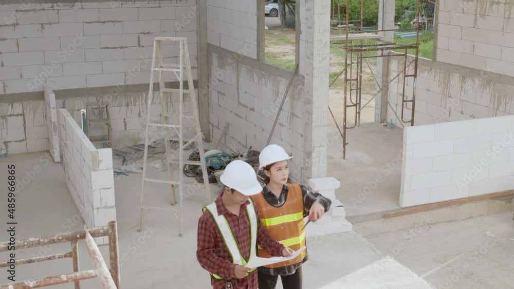 Poster architect and client discussing the plan with blueprint of the building at construction site