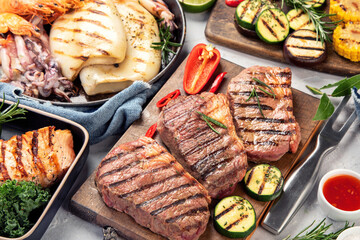 Grilled fish, seafood and meat assortment on light background.