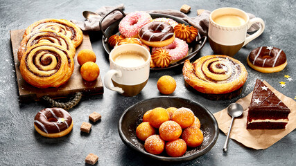 Table with various cookies, donuts, cakes and coffe cups