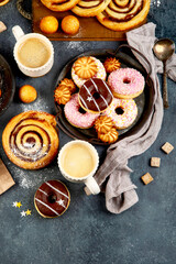 Table with various cookies, donuts, cakes and coffe cups