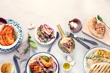 Grilled fish and seafood assortment on light background.