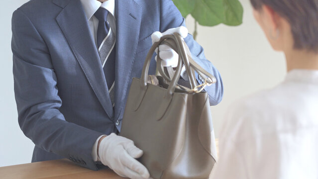 バッグの査定,鑑定をするアジア人男性