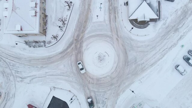 Cars Driving By The Slippery Roundabout And Snowy Road In Kragero, Norway At Winter. aerial top-down