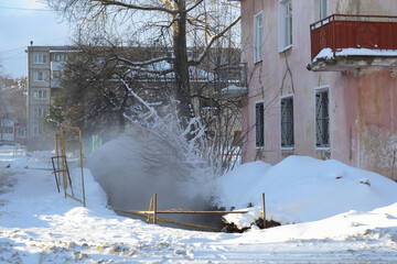 A metal fence at the site of a utility accident on a city street in severe frost. Steam release...