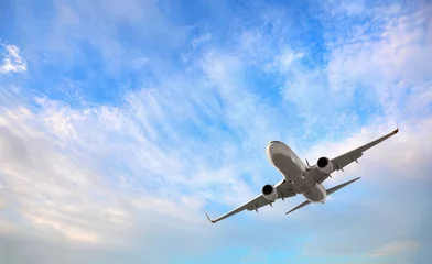Tuinposter Wit passagiersvliegtuig dat in de lucht vliegt, verbazingwekkende wolken op de achtergrond - Reizen per luchtvervoer © muratart
