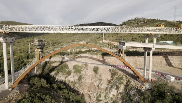 Lateral revealing motion video of a new bridge&acute;s structure under construction in Barranco de la Bota in Morella on a sunny afternoon