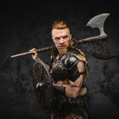 Fototapeta na wymiar Furious redhead viking with axe on his shoulder looking at camera