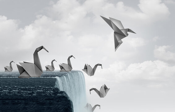 Adapt to survive concept as paper swans falling off a waterfall and one origami bird adapting new skills and flying away to safety.