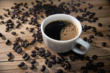 cup of coffee with roast beans on wood table