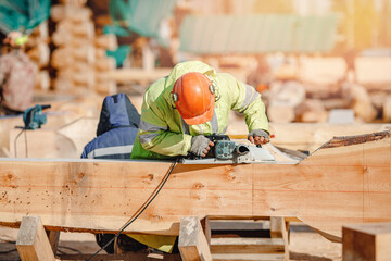 Industrial work carpenter grinds log with electric jointer, construction frame building site of...