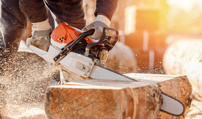 Close-up chainsaw of woodcutter sawing chain saw in motion, sawdust fly to sides. Concept is to...