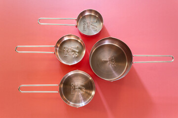 Collection of empty copper measuring cups on red background in top view