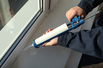 Construction worker sealing window with caulk, closeup