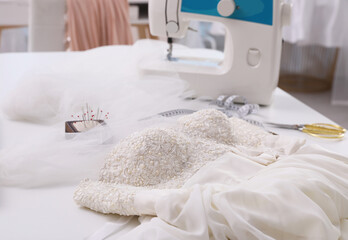 Beautiful wedding dress with embroidered bustline on table in dressmaking workshop