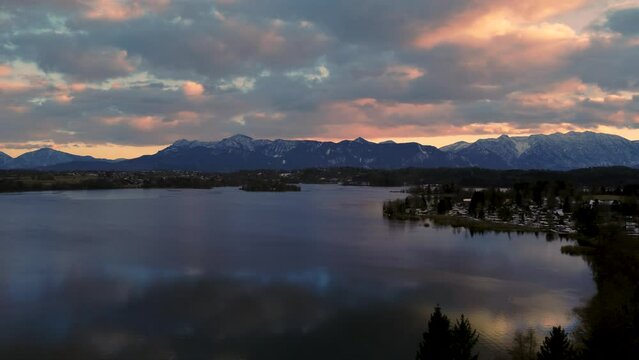 Panoramic view scenic Bavarian lake Staffelsee in south Germany close to the alps with a  vibrant dramatic sunset cloud sky and idyllic mountains and deep blue reflecting water. Aerial drone footage