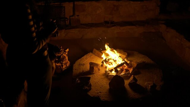 Slowmotion moving angle of a warm comforting campfire at night with friends gathered around in foreground