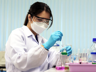 The scientist wears PPE do the chemical experiment in laboratory, with pale pink solvent solution from pouring reaction indicator acid titration experiment, analysis compounding in wastewater sample.