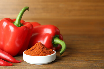 Paprika powder and fresh peppers on wooden table. Space for text