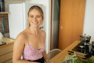 Happy and healthy young woman meal prepping whole vegetarian meal in the kitchen. High quality photo
