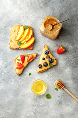 set of various toast with whole grain bread, peanut butter, honey, mint, peanut, nectarine, blueberry and strawberry. healthy breakfast concept. peanut jar